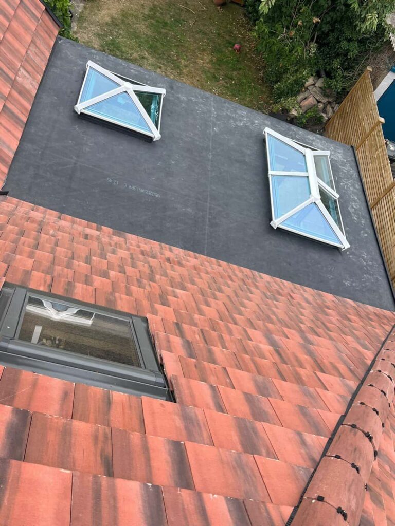 This is a photo taken from the roof ridge looking down a tiled pitched roof on to a flat roof. Works carried out by Erith Roofing Repairs